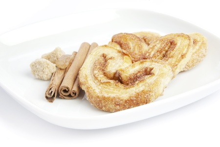 Cookies, sugar and cinnamon sticks on white plateの写真素材