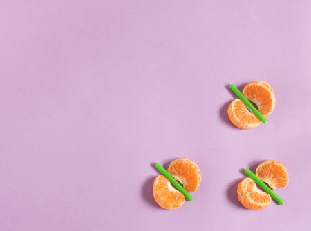 Slices of tangerine with green sticks like butterflies,  on pastel pink background flat layの写真素材