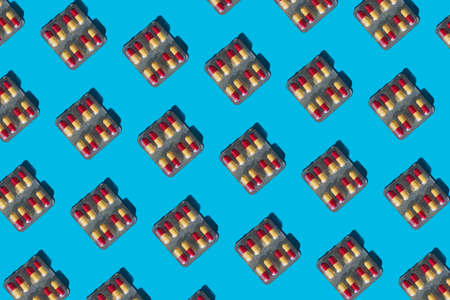 Package of red-yellow pils lay out on blue background, minimal concept patternの写真素材