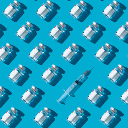 Vaccine vials and syringe on a cyan background , flat lay pattern minimalistic conceptの写真素材