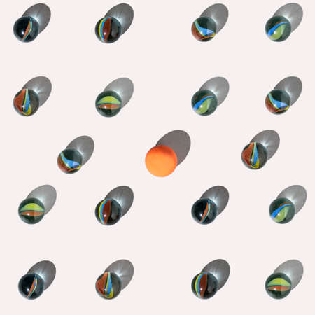 Glass marbles and a rubber ball with shadows, lay down on a white background. Flat lay square...