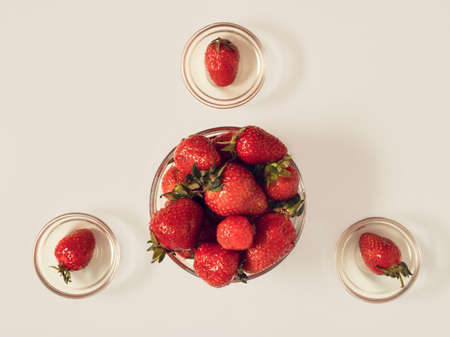 Ripe red strawberries lay down in transparent glass pots, on white background. Flat lay summer refreshing conceptの写真素材