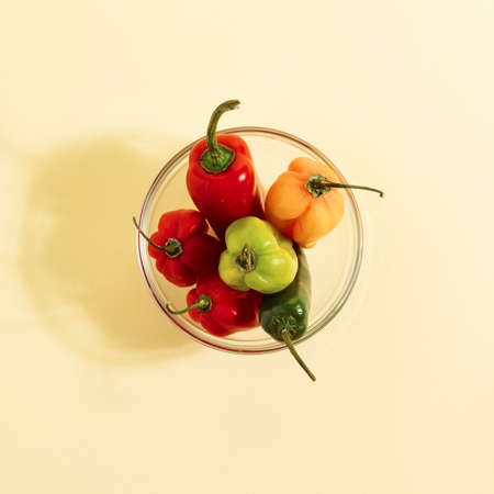 Jalapeno and habanero hot chili peppers in glass bowl, on a yellow background, minimal flat lay...