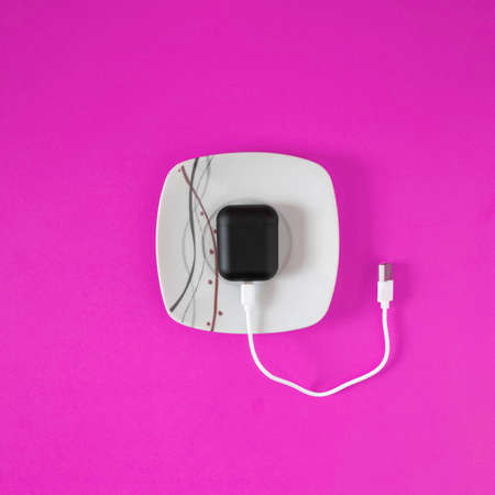 Wireless ear phones lay down on white ceramic plate. Minimal entertaiment concept, flat lay...
