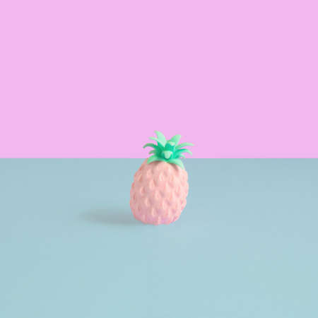 Colorful artificial pineapple stand on pastel pink and cyan background. Square composition, minimal summer decoration conceptの写真素材