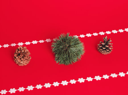 Decoration ball made of pine tree, pine cones and snowflakes stand on pastel red background. Minimal horizontal composition,  Christmas and New Year abstract decorative  conceptの写真素材
