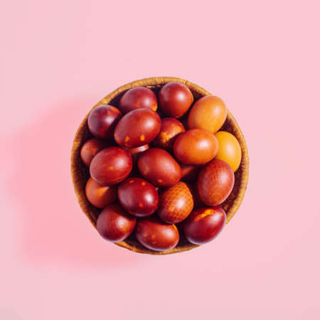 Easter eggs in a basket against patel pink background. Flat lay square composition, minimal Easter Holiday decoration conceptの写真素材