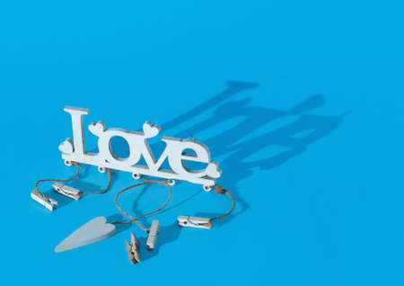 Wooden word LOVE on pastel cyan background with fancy shaddow. Minimal horizontal composition,...