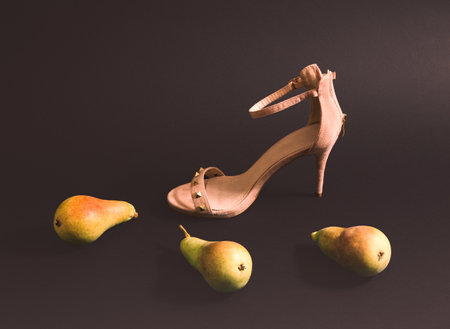 Pears and high heels on a black background. Minimal horizontal composition, modern woman lifestyle conceptの写真素材