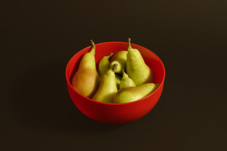 Pears in red bowl on a pastel red background. Minimal horizontal composition, heatlthy eating conceptの写真素材