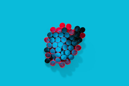 Top view on a bunch of red and black straws against blue background. Minimal flat lay horizontal composition, colors and shapes conceptの写真素材