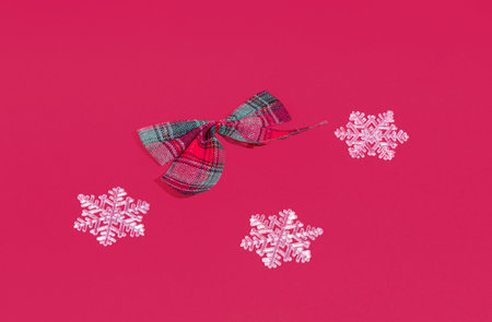Decorative bow and sbowflakes on red background. Minimal horizontal composition, Christmas and New...