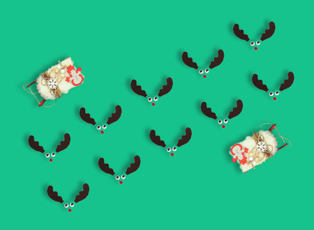 Red nosed reindeers and SantaÂ´s sleigh on pastel green background. Square flat lay seamless pattern composition, minimal creative funny Christmas celebration conceptの写真素材