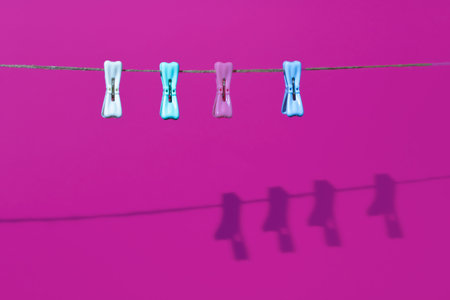 Clothespins on the rope with shadow on a purple background. Minimal horizontal composition, colors beauty conceptの写真素材