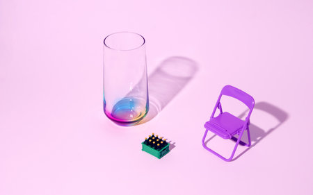 Multicolored glass, garden chair and bottle crate on a pink background. Minimal horizontal composition, summer refreshment conceptの写真素材