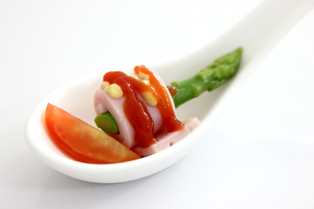 Ham wrapped asparagus topped with a tomato sauce.の写真素材