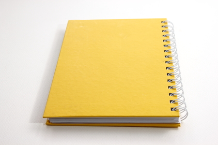 A yellow notebook with a white background.の写真素材