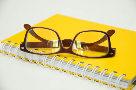 writing pen ready for taking notes on a  notebook   paper  glasses over white.の写真素材