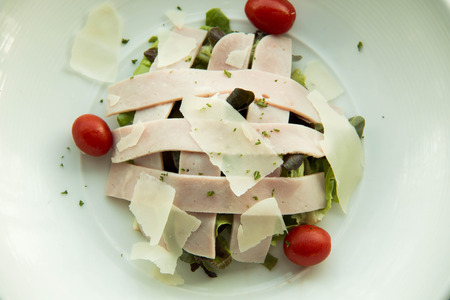 Pieces of ham and cheese with salad on white plateの写真素材