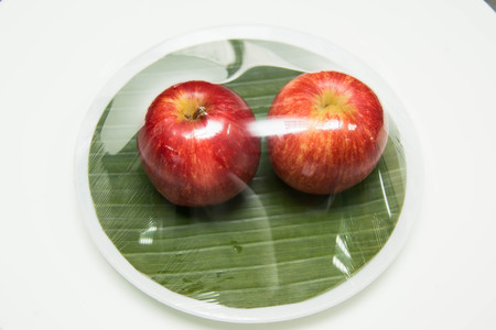 A Red apple's two on with banana leavesの写真素材