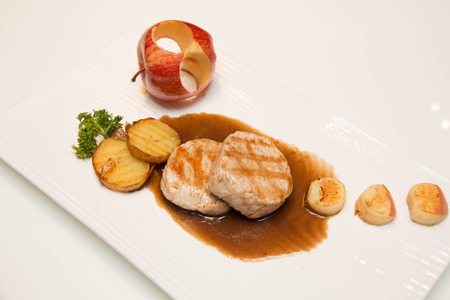 Pork meat grilled with potato  and apple sauce on a white plateの写真素材