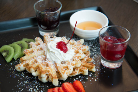 Belgian waffles with strawberry, kivi, blueberry, cherry and sweet sauceの写真素材