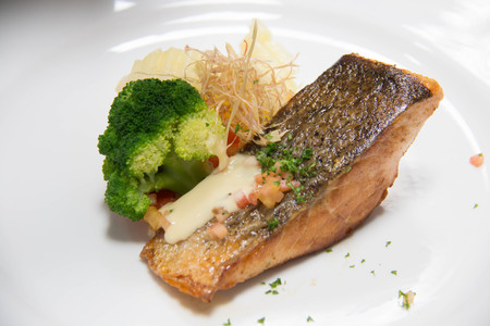 Tasty grilled salmon steak on mixedl vegetables with sauceの写真素材