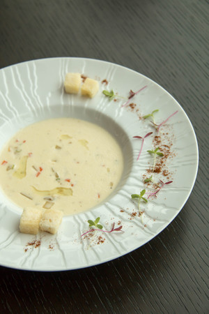 cream soup in a white bowl on wood tabelの写真素材