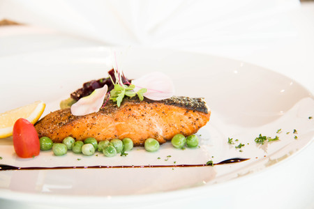 Tasty grilled salmon steak on mixed colorful vegetables background