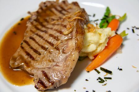 A beef steak with brown sauce and vegetables