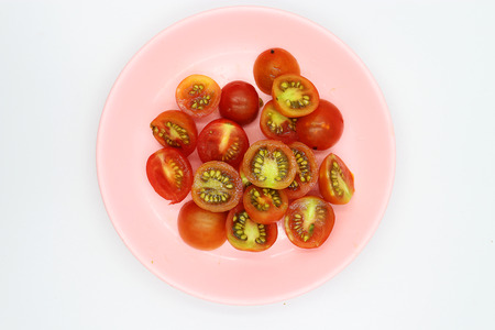 shopped tomatoes in pink dish on white background.の写真素材