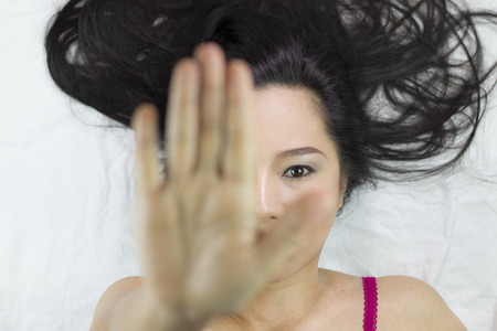 moody asian women  lying on ground with black long hair. acting upset , unhappy, and showing stop gestureの写真素材