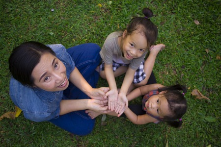 Lifestyle portrait mom son and daughter in happiness at the outside in the meadow, Funny Asian family in a green park High resolution image gallery.の写真素材