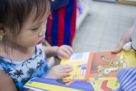 CHIANG MAI,THAILAND-MAY 3,2019 : Little Child explores the bookshelves with mom in book store. High resolution image gallery.のeditorial素材
