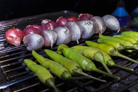 Garlic Shallot and fresh chili peppers roasting over a charcoal fire grill. prepare for cooking Thai food. High resolution image gallery.の写真素材