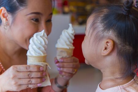 Mom and little child eating ice scream cone  together . feeling enjoyment.  High resolution image gallery.の写真素材