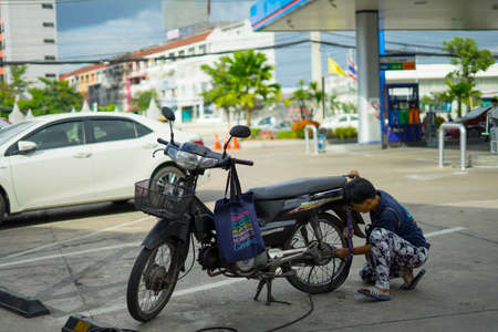 CHIANGMAI,THAILAND-Nov 14, 2019 :  Thai man biker inflating the tire of motobike. in PTT Gas station.のeditorial素材