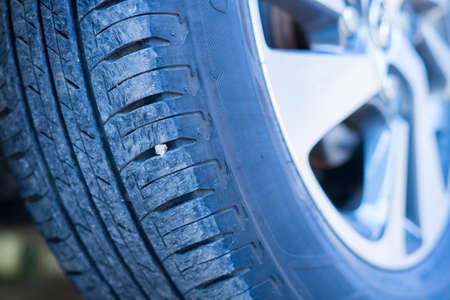 Close up of stones stuck on front of car tyre.の写真素材