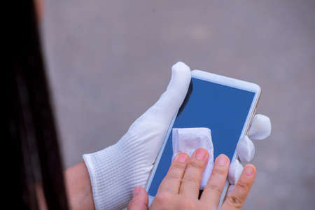 young asian woman cleaning mobile phone screen with soft paper napkin.の写真素材