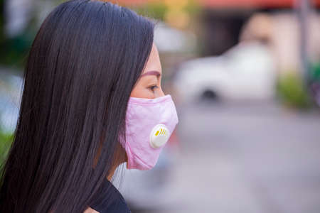 Asian women wearing mask prevent, protection  virus  in the city blackground .の写真素材