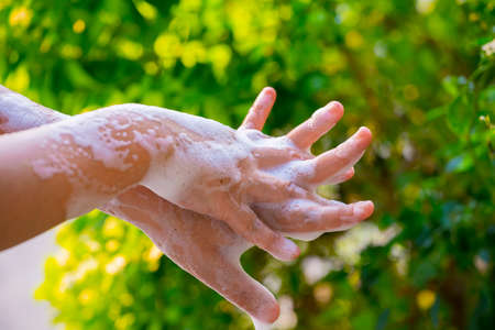 women washing hands with soap and water on green blur background.