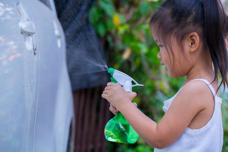 Asian children spry soap to clean car door handle.の写真素材