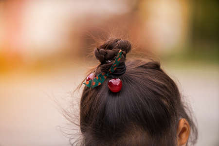 Asian girl's hairstyle with a braid around her head close-up. Hair styling is done with hairpins and...