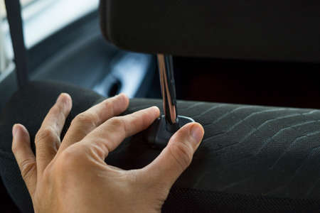 Hand adjusts headrest in car interior. adjusting the seat position in the car