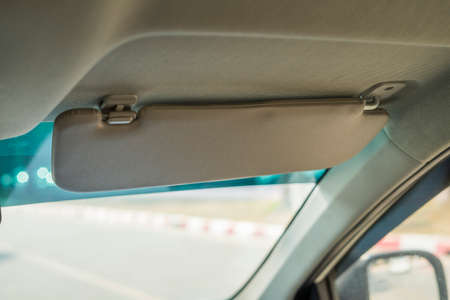 Car visor. Car interior. Grey open sun car visor with selective focus and car mirror on blurred background with automobile windowの写真素材