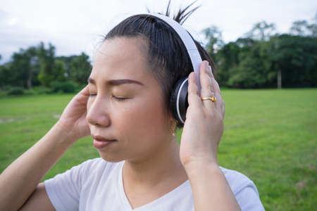 Cute asian woman listen to music and holding white headphone, back shot.