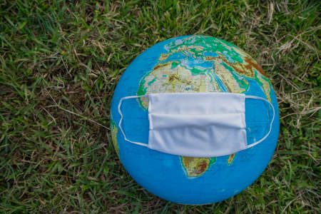 Corona virus concept, Earth with face mask protect on green grass.の写真素材