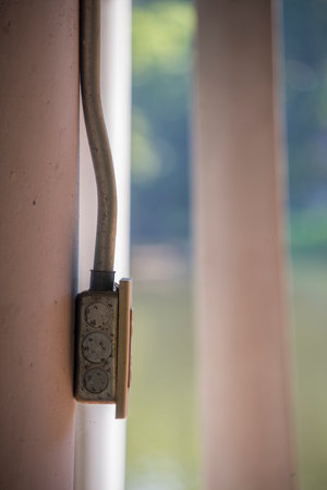 Plastic electric plug on concrete wall with steel tube.
