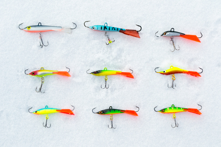 Different types of winter lures balancers for predatory fish. Large and small balancers for catching fish from the ice. Baits in the snow.の写真素材