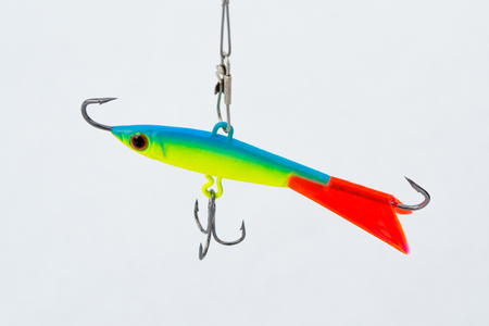 Winter bait balancer for predatory fish. Bright yellow with green balancer. With red fin. On the background of white snow.の写真素材